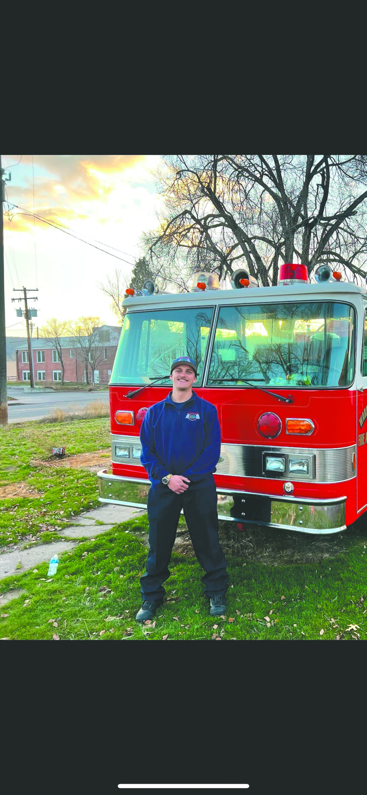 Firefighter poses in front of a fire engine