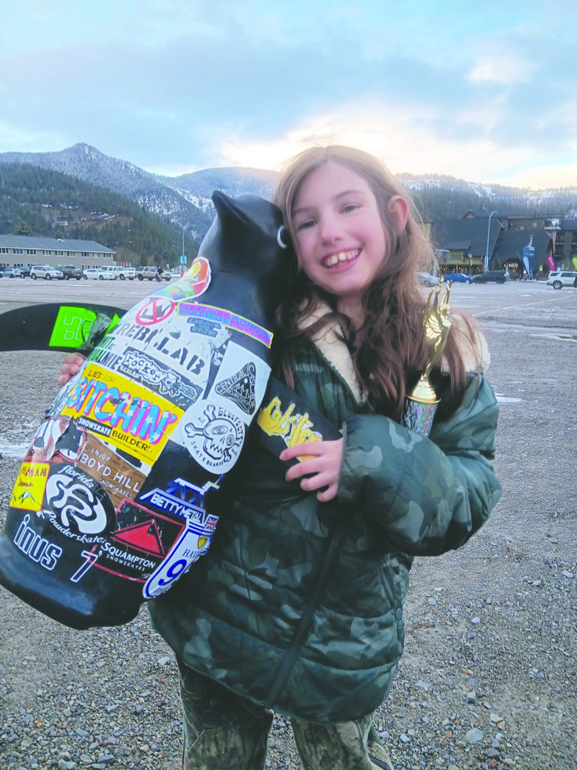 a sandy student holds up a penguin stature covered in stickers, her trophy