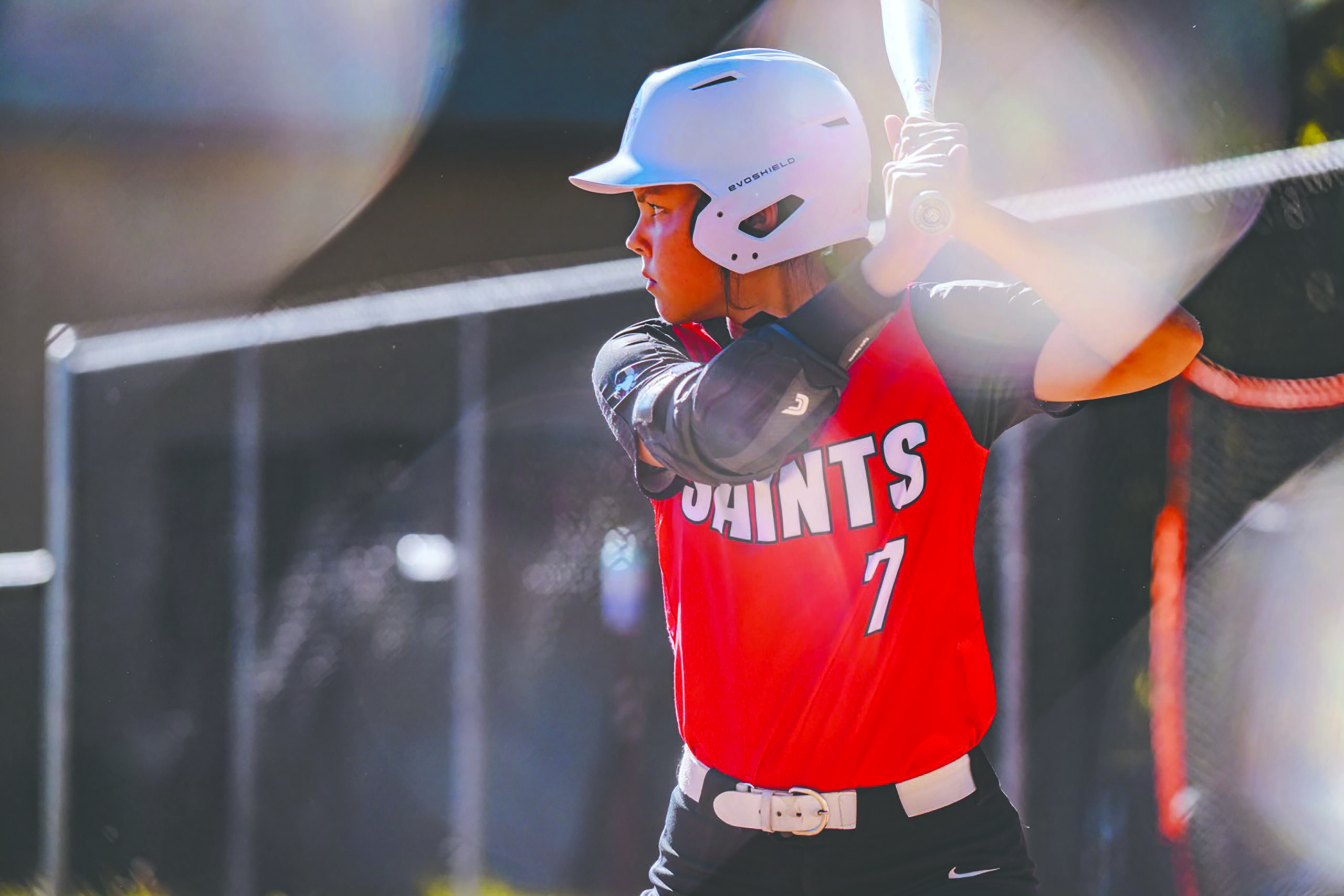 girl swings her bat to hit the ball