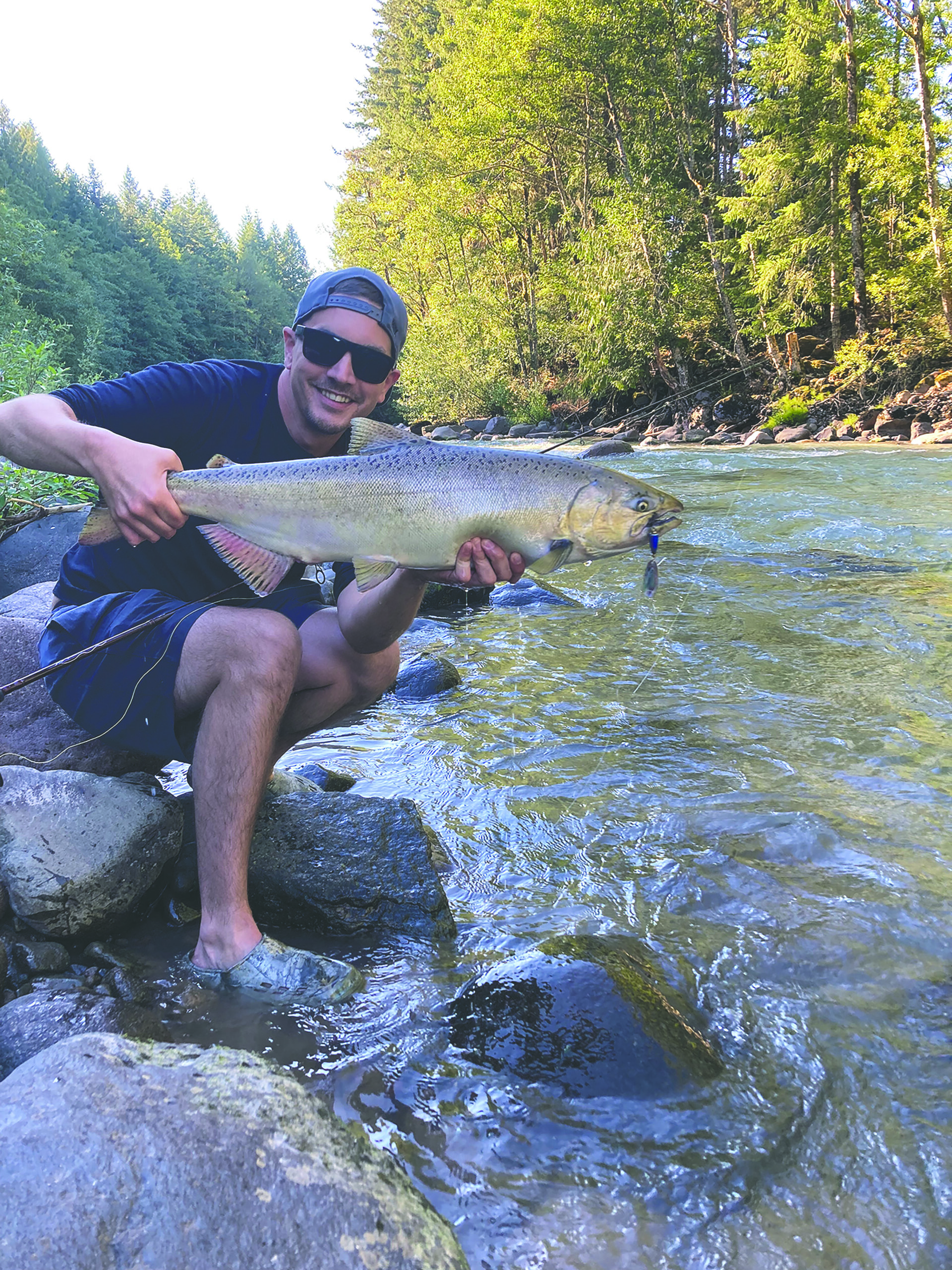 man holding a salmon on the banks of the river