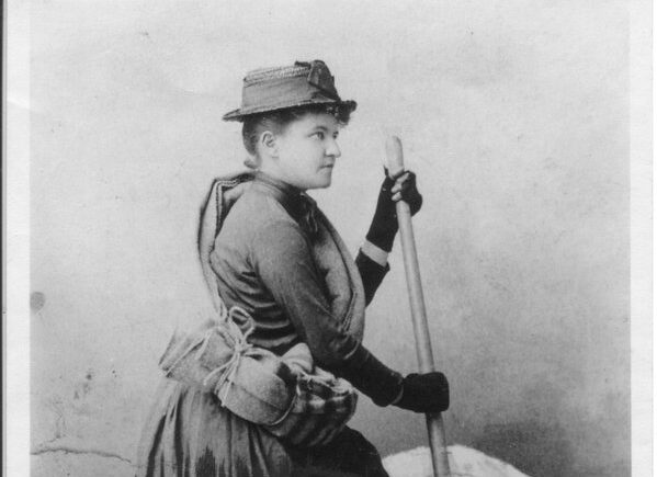 an old photograph of Fay Fulling in a Victorian winter dress, ready to climb with the help of a hiking pole.