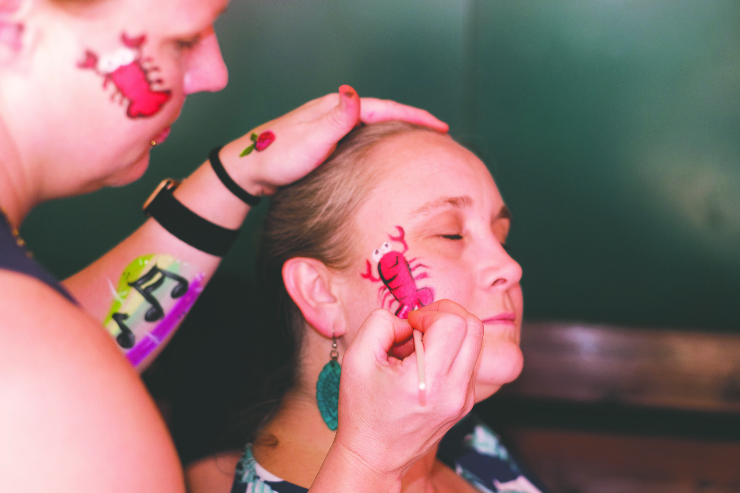 a woman gets a lobster painted on her cheek