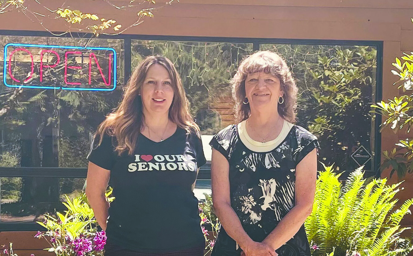 tow woman stand in front of the Hoodland senior center welcoming guests