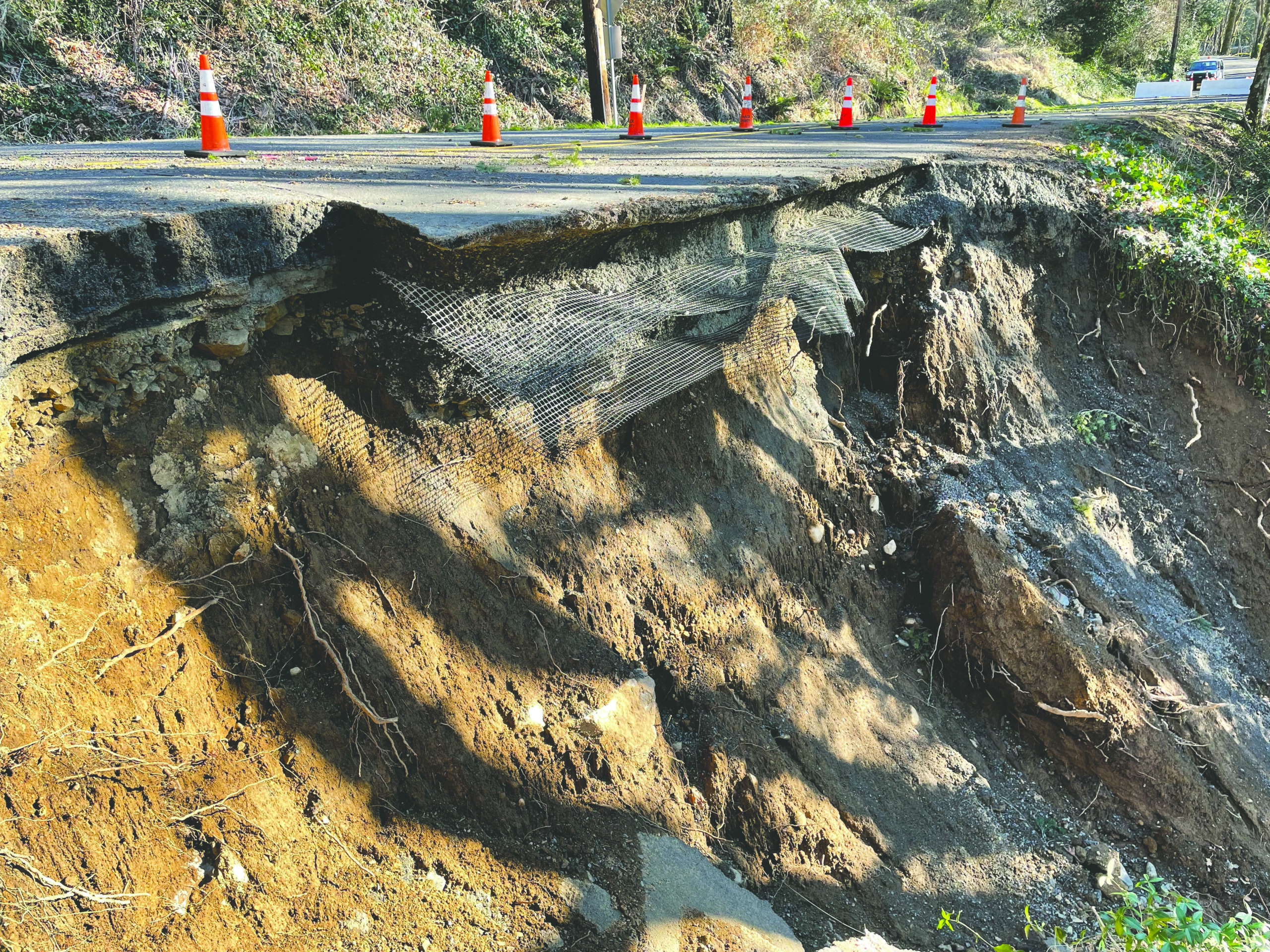 a blocked off section of road that has slide down a cliff