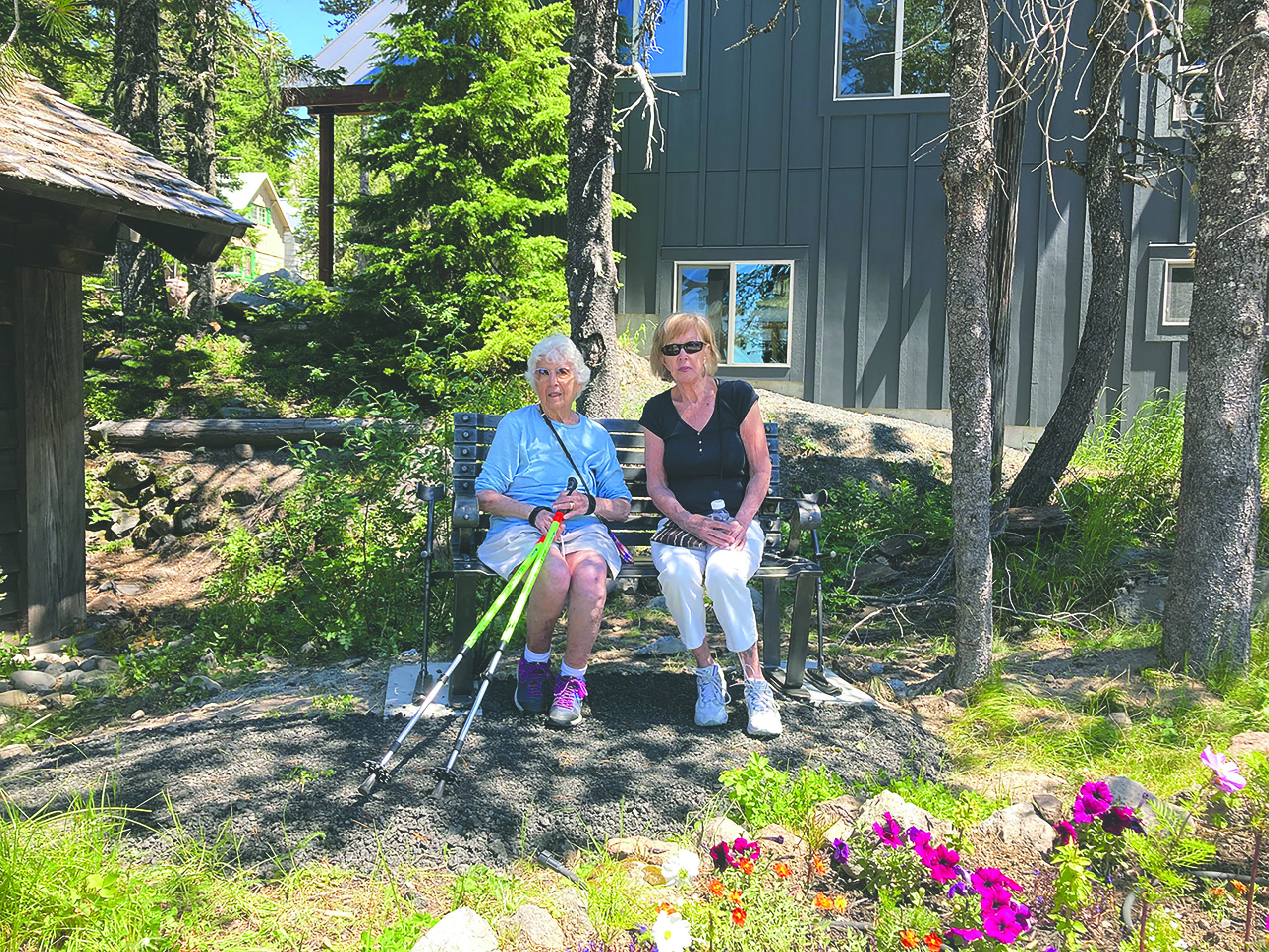 two friends sit on a memorial bench