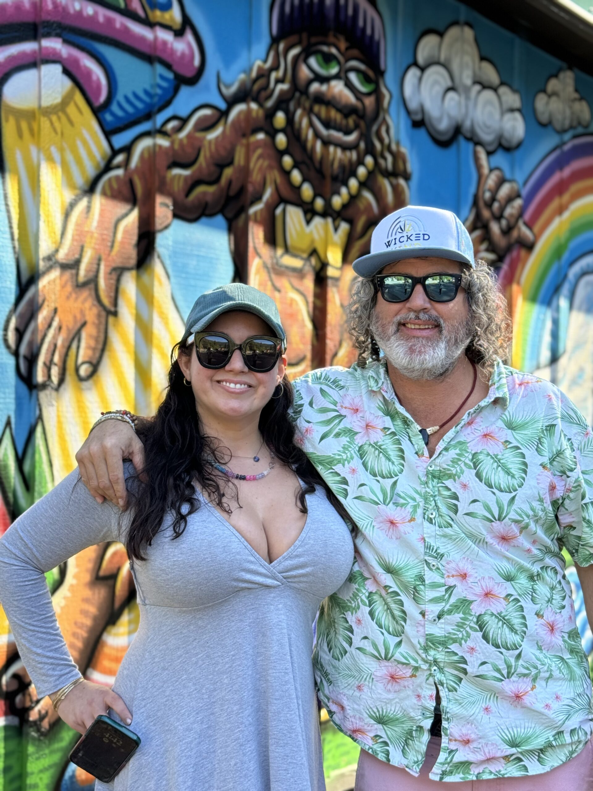 co-owners pose in front of a colorful mural