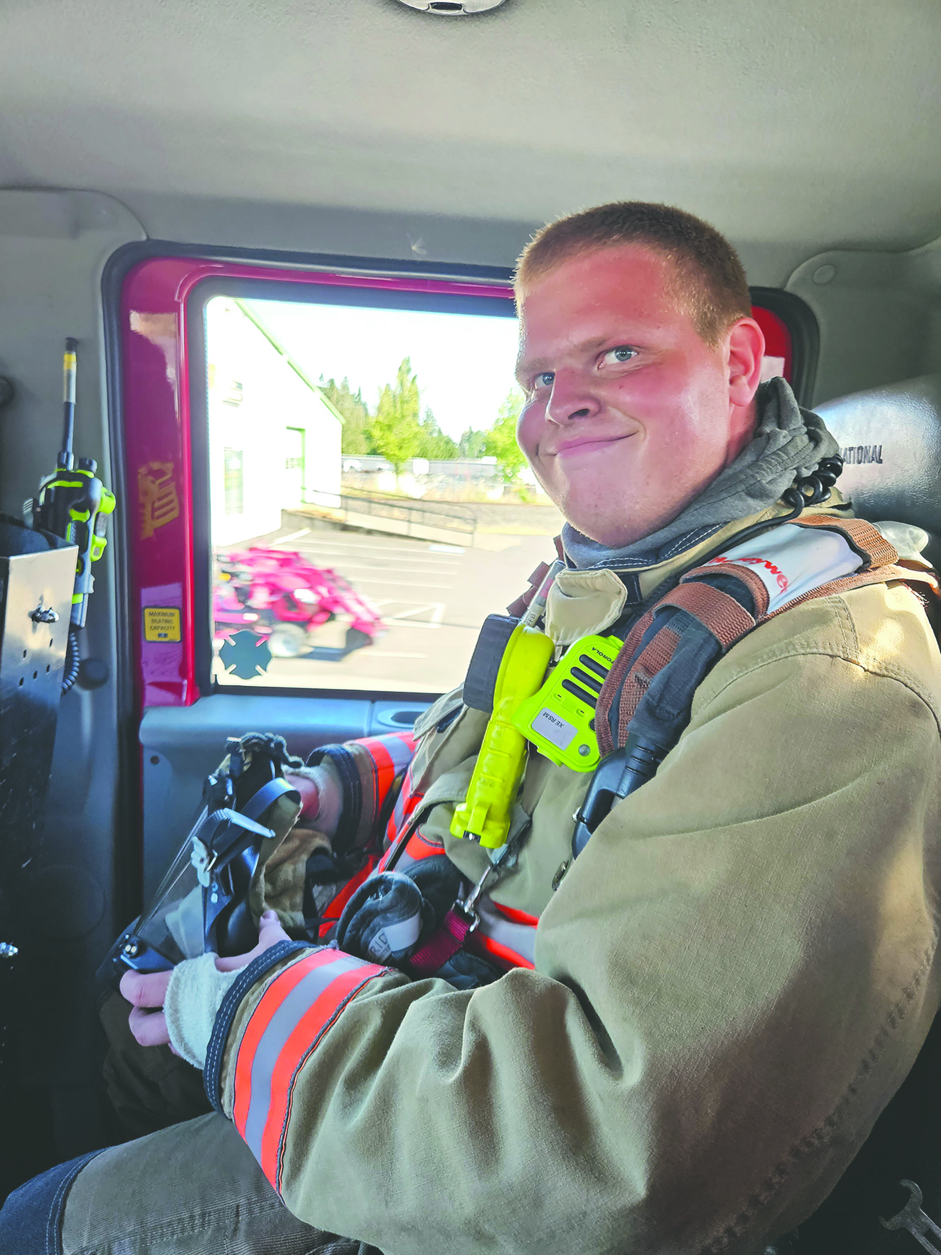 Fire fighter Jacob sits in the back of a fire truck in full gear