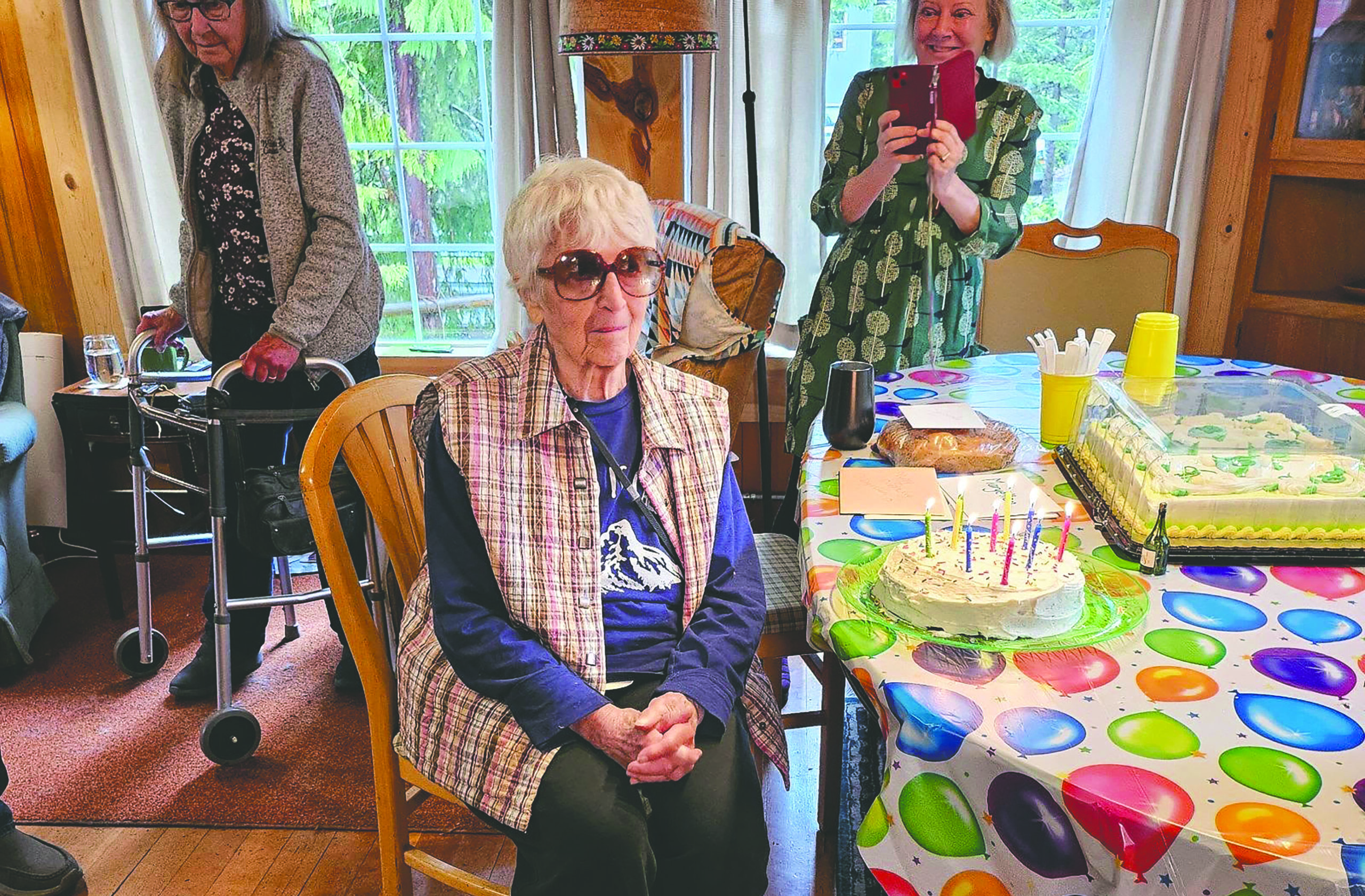 Maryellen sits at a decorated table admiring her 90th birthday cake