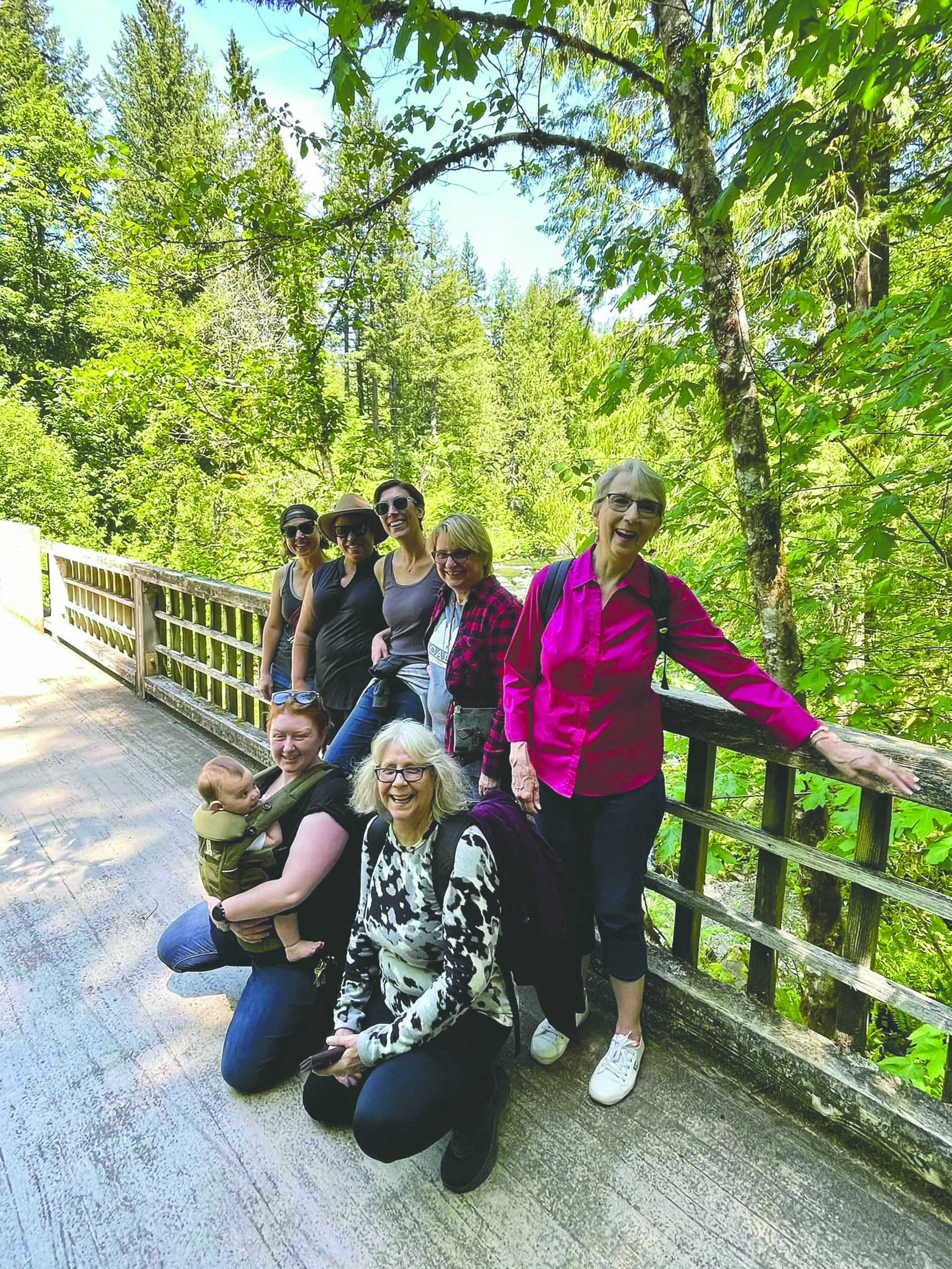 hoodland woman's club takes a group photo on a forest bridge