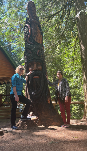 two hikers standing next to a carved tree