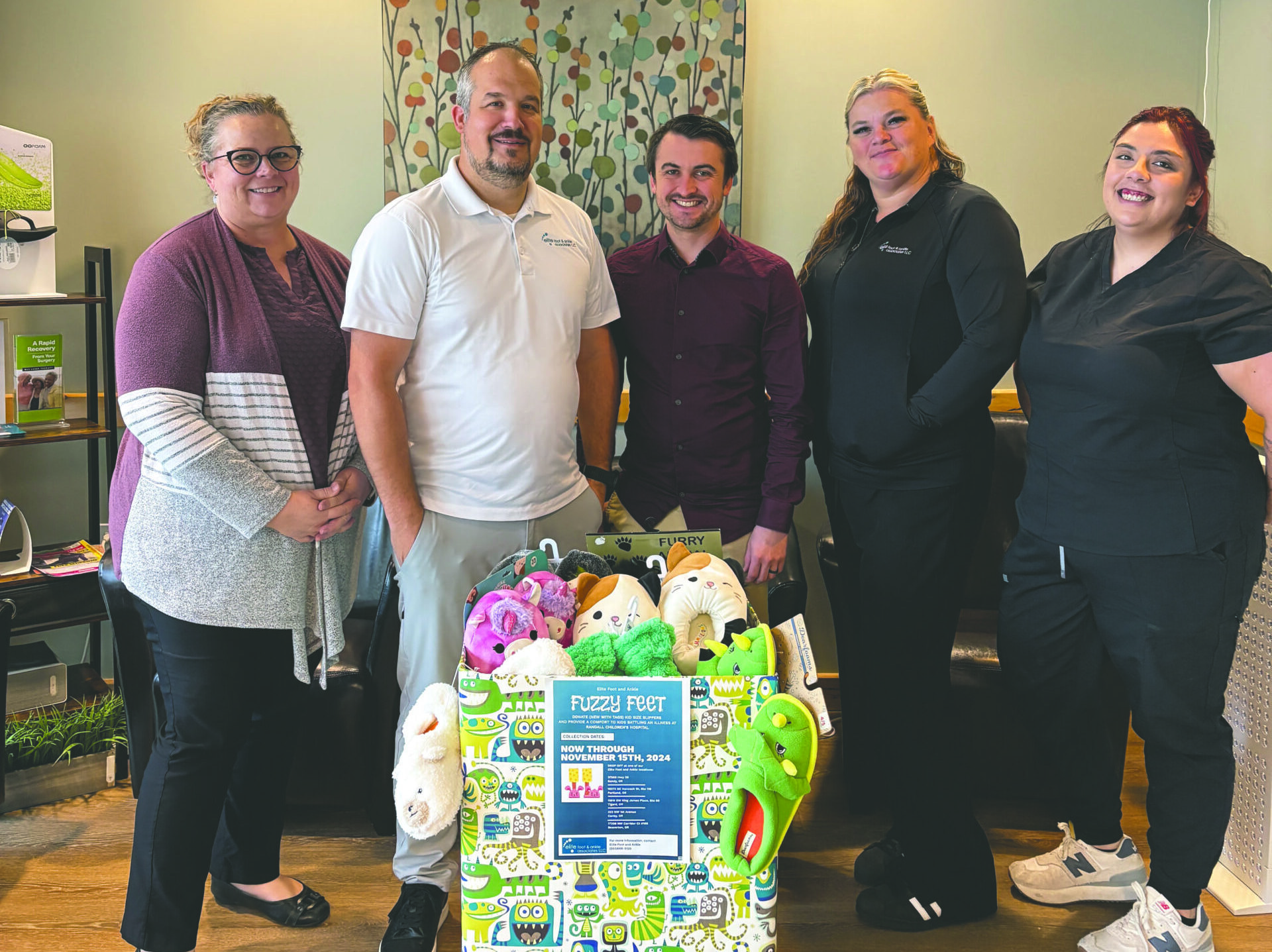 Volunteers stand behind a donation box full of slippers