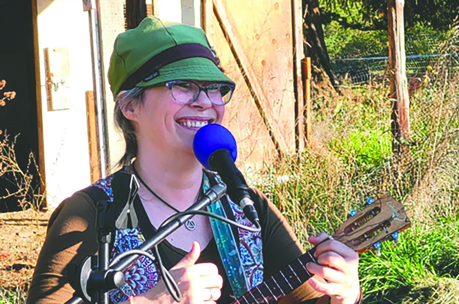 Woman smiles while playing the guitar on stage