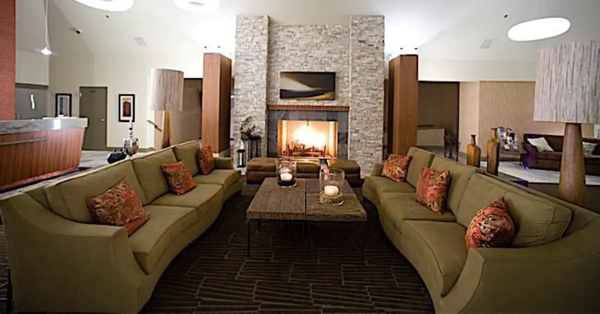An image of a hotel lounge with couches on either side and a large fireplace in the back.