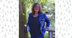 Paula Siverly stands next to a large fir tree